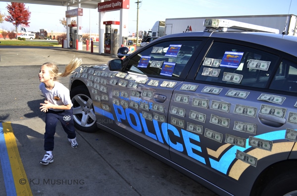 Bethany Baker, 7, of Stafford quickly places a dollar on an Aquia Harbour police cruiser for Special Olympics before shyly running off. (KJ Mushung/PotomacLocal.com)