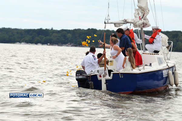 Following the christening of the Benjamin Chase, a new boat for Sea Scout Ship 100 of Gainesville named after two Cub Scouts killed at the Sandy Hook Elementary School massacre, the victim's mothers tossed rose petals into the Potomac River in honor of the victims. [Mary Davidson / Potomac Local News]