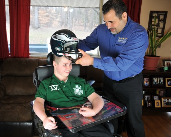 Basim Mansour, owner of Michael and Sons Services, presents 15-year-old Brandon Anderson a Philadelphia Eagles helmet signed by Brandon's favorite player Michael Vick. (Photo; Mary Davidson/PotomacLocal.com)